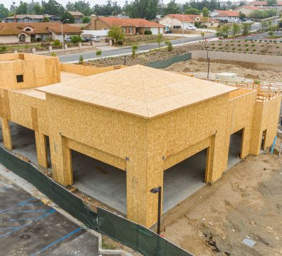 House construction in progress with a visible wooden frame, showing beams and studs