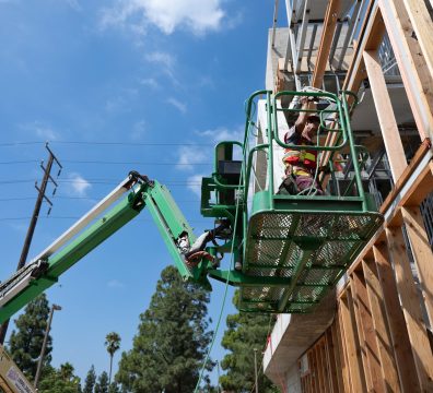 A house being built with a visible wooden frame, including structural beams and studs.