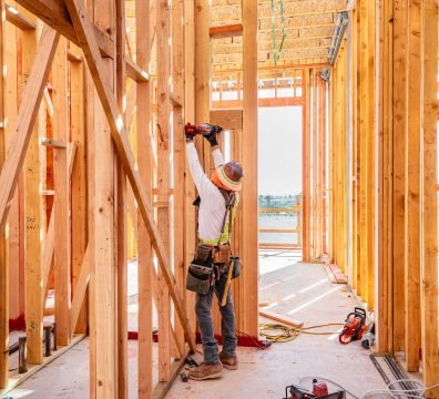 A house in the framing stage with wooden beams and studs forming the structure