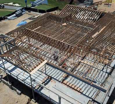 Construction of a house featuring a wooden frame with beams and studs visible
