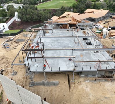 Wooden house framing under construction, with structural beams and studs visible.