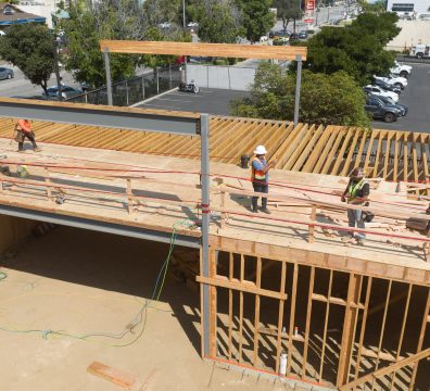 Wooden house frame in progress, showing structural beams and studs.