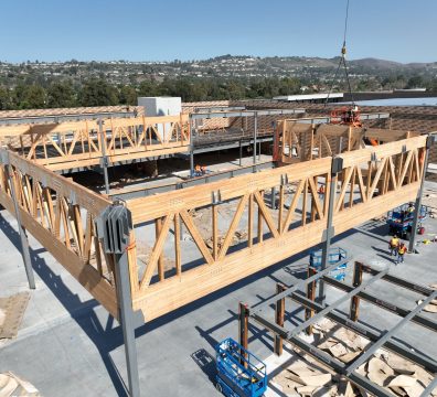 A house being built with a visible wooden frame, including structural beams and studs