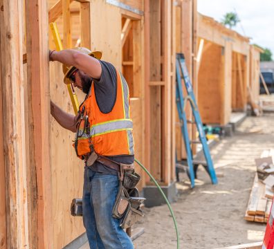 House construction with an exposed wooden frame, featuring beams and studs.