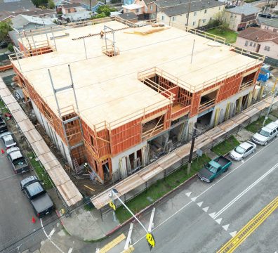 An in-progress house with a wooden frame, featuring exposed beams and studs.