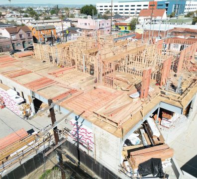 An under-construction house with a wooden frame, displaying the structural beams and studs.