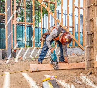 Building a home: wooden frame with structural beams and studs visible.