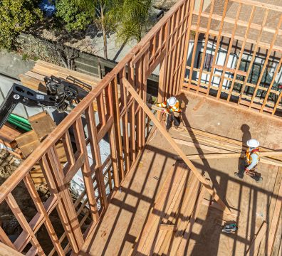 Wooden structure of a house under construction, featuring the framework of walls and roof.