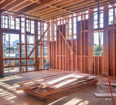 The bare wooden frame of a house under construction, highlighting the structural beams and studs.