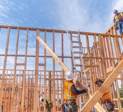 A house's wooden frame under construction with walls and roof beams exposed.