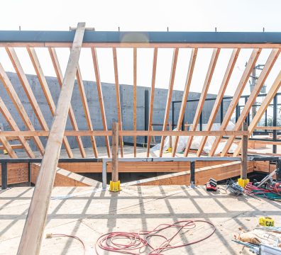 A house in the framing stage, with wooden beams and studs forming the structure.