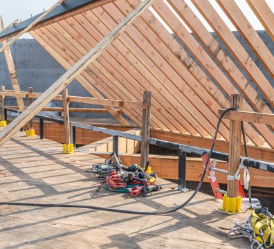 Exposed wooden framing of a house under construction, showing structural beams and studs.