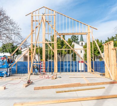 Under construction: a wooden house frame with walls and roof beams in place.